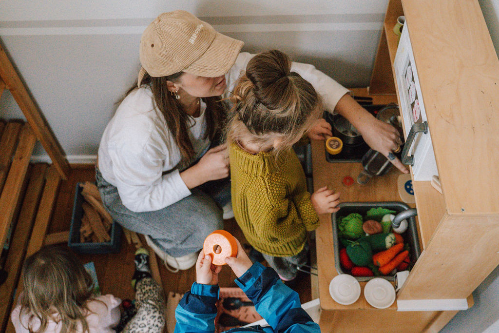 Mutter und Kinder spielen an der Kinderküche im Picknick