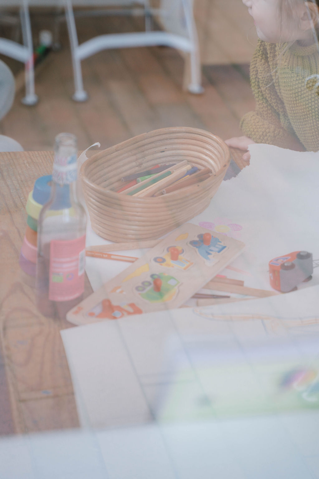 Kind mit Buntstiften und Holzpuzzle am Tisch